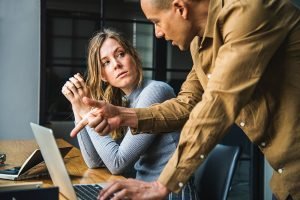A man explaining to a woman something on a laptop