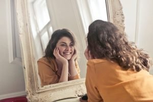 Woman who's smiling in front of the mirror.