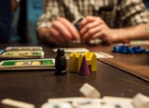 Person holding cards, table with cards and figurines
