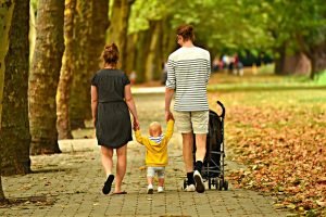 Man and woman walking with a toddler and strollers 