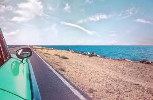 A car driving along a beach in summer.